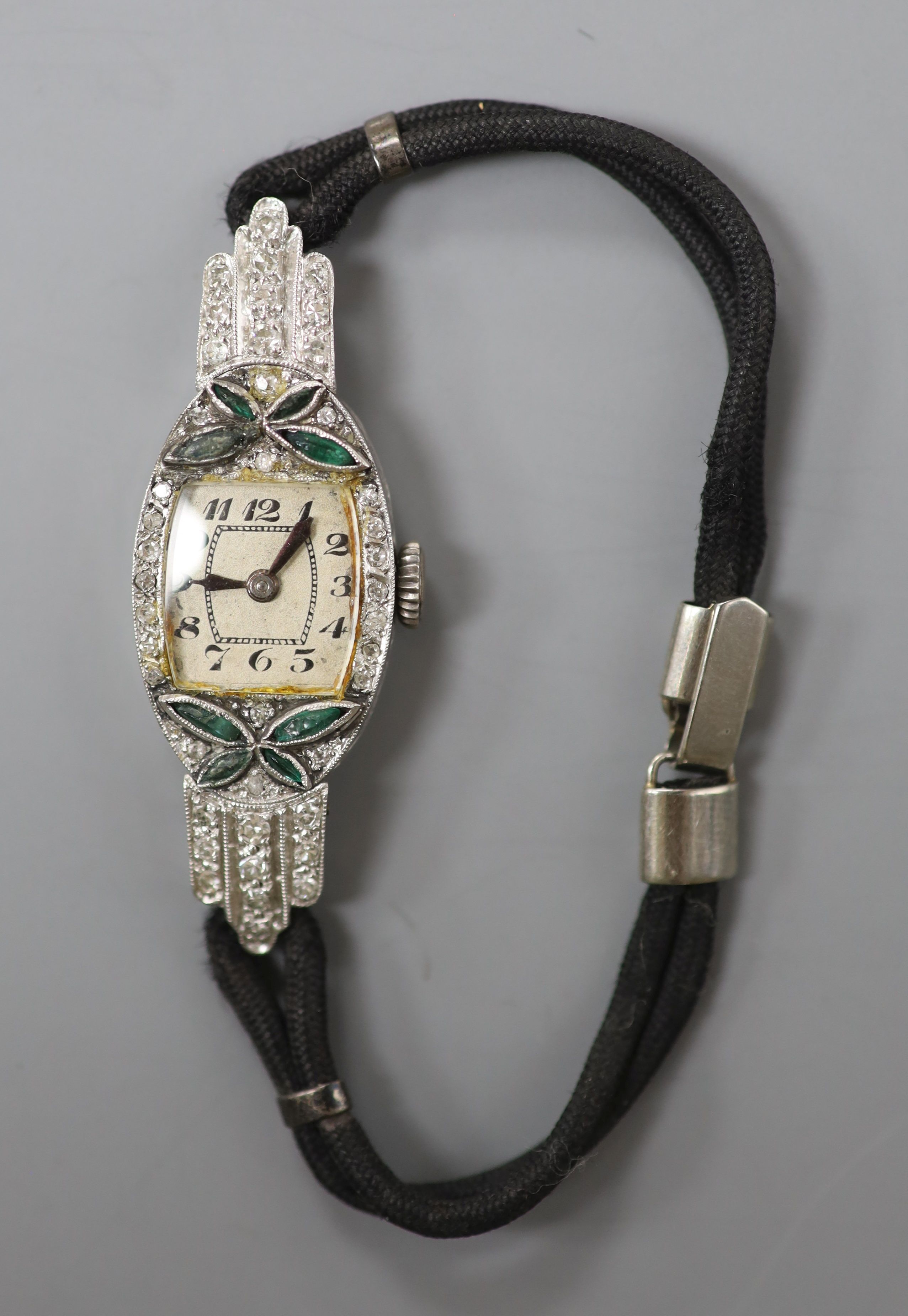 A lady's 1940's/1950's white metal (stamped platinum), emerald? and diamond set cocktail watch, on fabric strap, gross weight 14.3 grams.